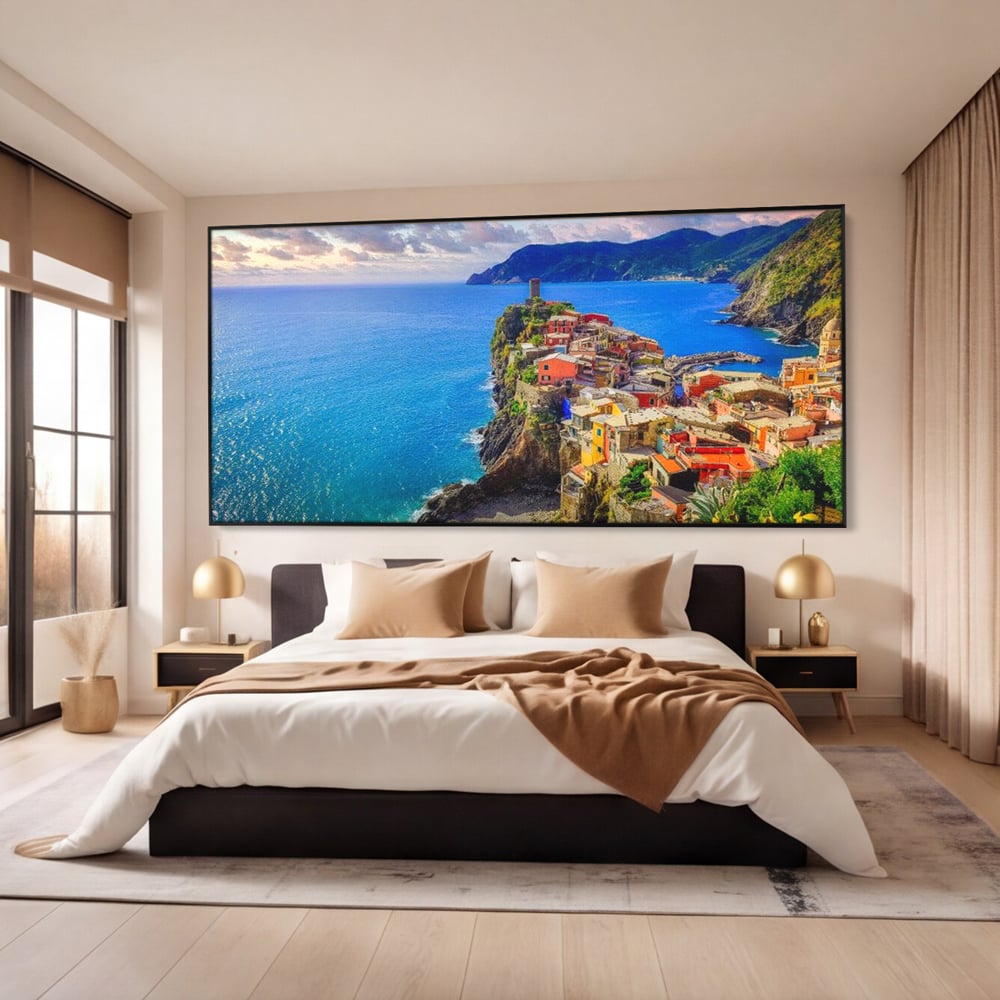 Tablou canvas cu peisaj costier italian cu sat colorat pe stanca, in rama de aluminiu negru, pe perete intr-un dormitor